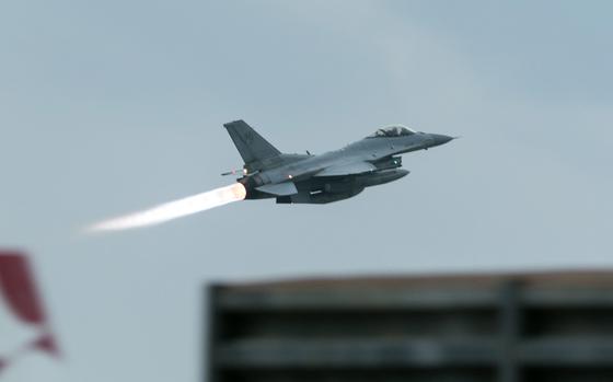 A flame shoots out from the back of a fighter jet as it takes off.