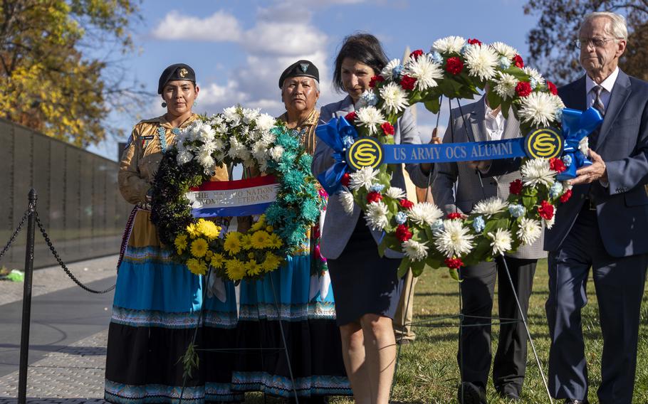 Two pairs of people each carry a wreath of flowers.