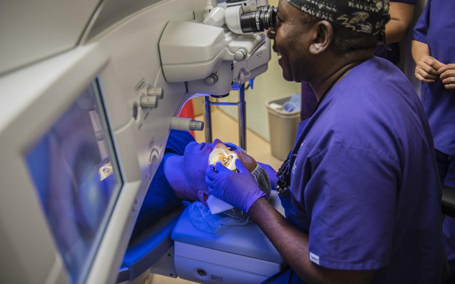 A doctor looks though a microscope while performing laser-eye surgery on a patient.