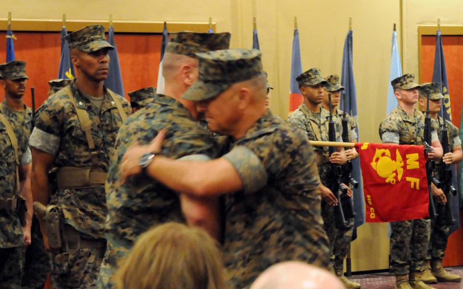 Brig. Gen. Adam Chalkley, outgoing commander of the 3rd Marine Logistics Group, embraces his successor, Brig. Gen. Kevin Collins, during a ceremony at Camp Kinser, Okinawa, Thursday, Aug. 29, 2024.