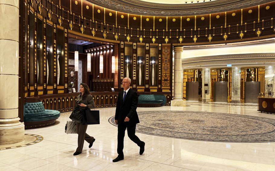 A man and a woman walk across the Ritz Carlton hotel.