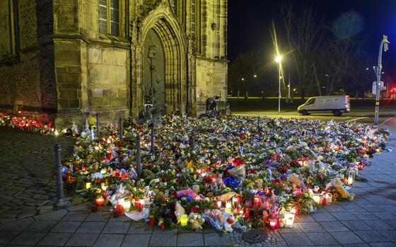 Flowers, candles, wreaths and stuffed animals lie in front of St. John's Church, Monday, Dec. 23, 2024, in Madgeburg, Germany, after a car drove into a Christmas market on Friday. (Klaus-Dietmar Gabbert/dpa via AP)