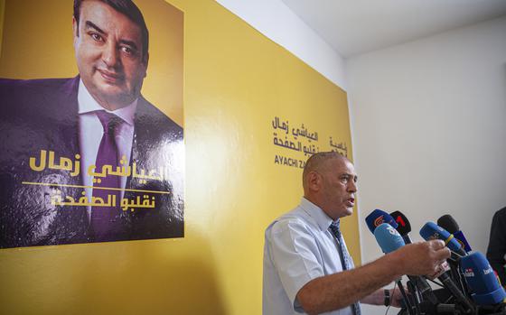 Abdessatar Messaoudi, right, attorney of Tunisian presidential candidate Ayachi Zammel, seen on the poster on the wall, speaks during a press conference after Zammel was sentenced to prison on fraud charges that Messaoudi decried as politically motivated, in Tunis, Monday, Sept. 16, 2024 (AP Photo/Ons Abid)