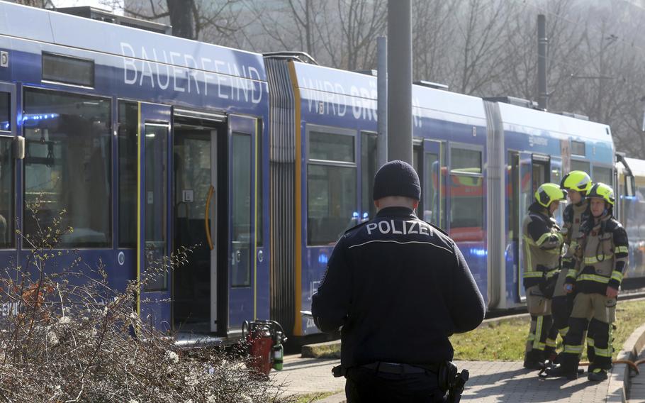 A police officer and emergency responders stand in front of a streetcar.