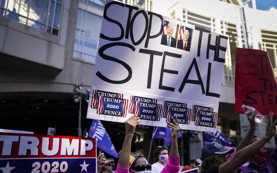 A woman holds up a sign reading “Stop the Steal” at a gathering in support of Donald Trump.