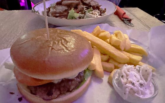 A blue cheese burger, served with fries and coleslaw at Bull and Bear restaurant and bar in Frankfurt. Gorgonzola cheese gives the burger a tangy zip. In the background is the Asian glass noodle salad.