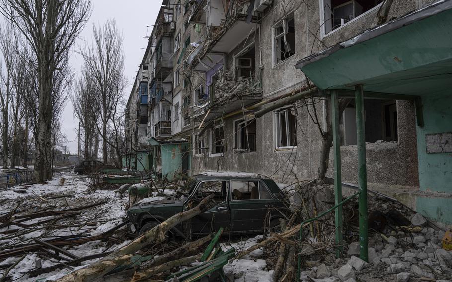 A destroyed car is seen in front of a residential building