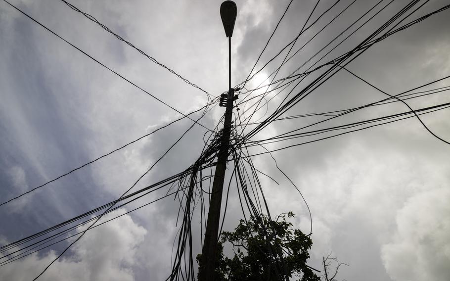 A utility pole with power cables streaming out from it in all directions.