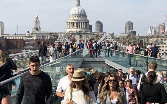 People walk across London's Millennium Bridge, with St. Paul's Cathedral in the background. Starting Jan. 8, 2025, most Americans, including U.S. service members and their families stationed in continental Europe, will need to apply for travel permission several days in advance of visiting or transiting through the United Kingdom while on leave.