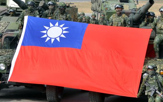 Members of Taiwan’s 564th Armored Brigade hold a flag after demonstrating their ability to repel an airborne attack near Kaohsiung, Taiwan, in January 2023.