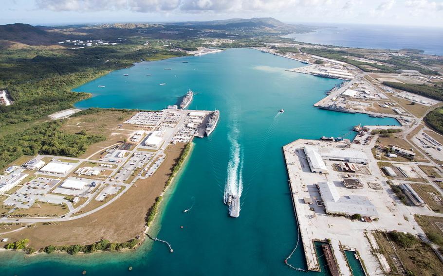 A vessel leaves the teal waters of Apra Harbor.