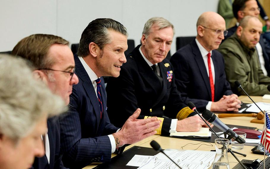 A row of men seated at a table with papers and microphones in front of them.