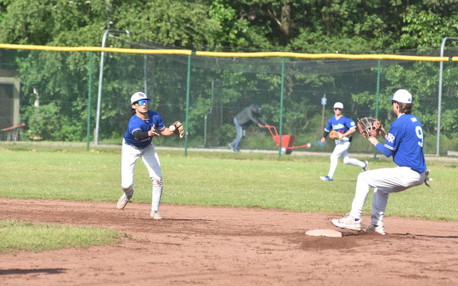 Ramstein shortstop Luke Seaburgh flips the ball to second baseman Liam Delp to try to start a double play Friday, May 24, 2024, at the DODEA European Division I championship game at Ramstein Air Base, Germany.