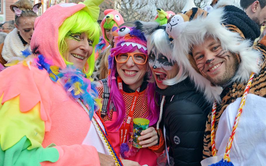 Four people in costumes, face paint and colorful wigs pose during a German festival.