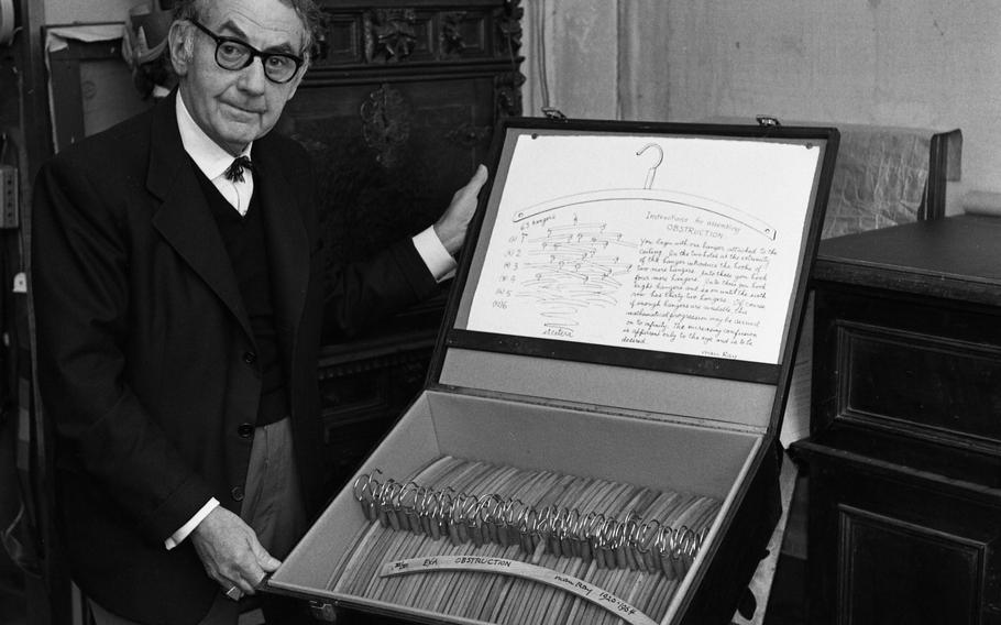 Man Ray - photographed in his Paris studio - shows "Obstruction," a replica made in 1964 of the original 1920 hanging sculpture piece comprised of 63 wooden coat hangers.