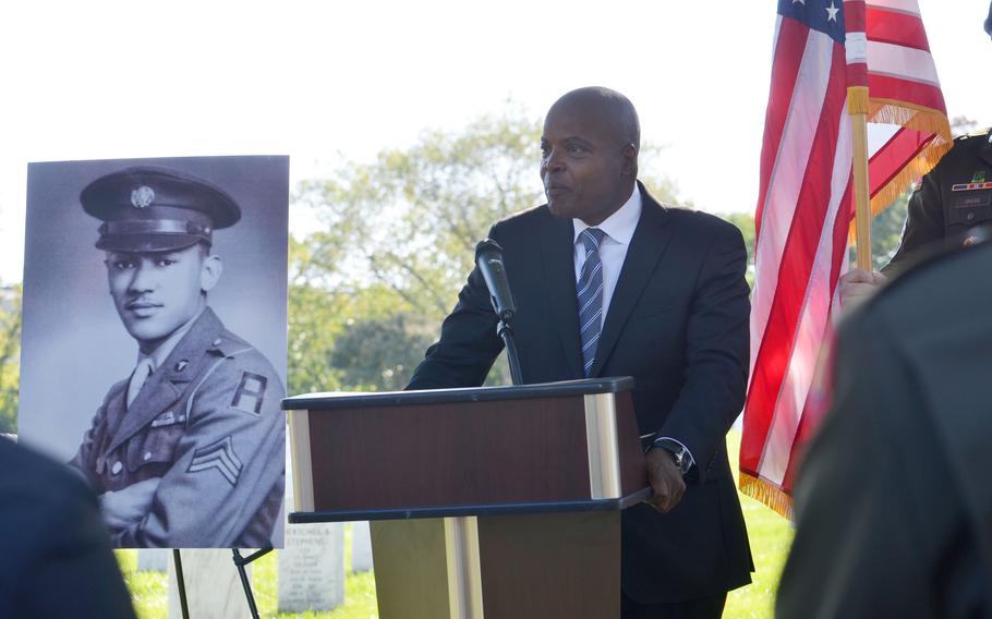 Retired Army Lt. Gen. Stephen Twitty with a photo of Waverly Woodson over his shoulder talks to the crowd about what it meant to be at the medal ceremony at Arlington National Cemetery, Va., on Wednesday, Oct. 11, 2023. Woodson, an Army medic, posthumously
received the Bronze Star and Combat Medic Badge for his heroics during the D-Day invasion during World War II. 