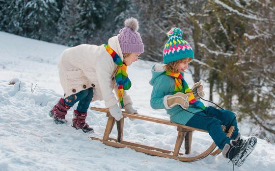  Boy and girl having fun with a sleigh in winter. 