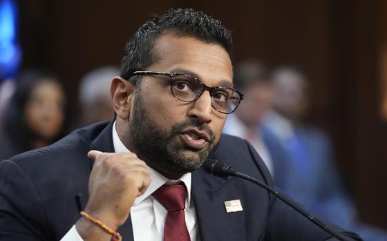 Kash Patel, wearing a dark suit and black-rimmed glasses gestures with his hand while speaking into a microphone during a congressional hearing.