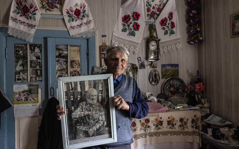 Fedir Bovkun holds a portrait of his father, Gerasim Bovkun. Fedir Bovkun was 6 years old when German occupiers nearly wiped out his Ukrainian village during World War II. Now, he worries about being attacked by invading Russians.