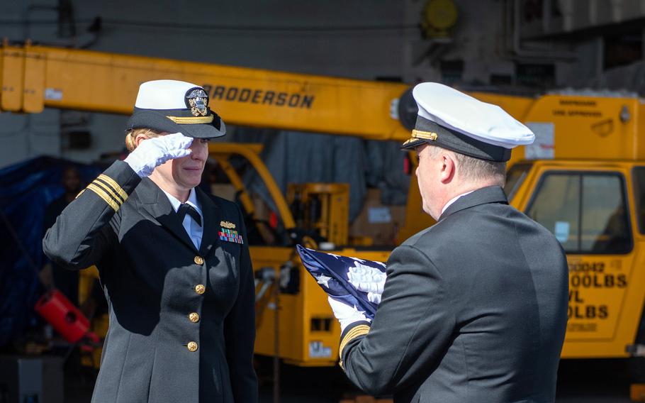 Capt. Daryle Cardone, commander of the aircraft carrier USS Ronald Reagan, presents the flag to Lt. Cmdr. Alisen Rockwell, wife of former Navy junior officer Marc Rockwell-Pate, during her husband’s burial at sea in the Pacific Ocean, Sept. 30, 2024. 