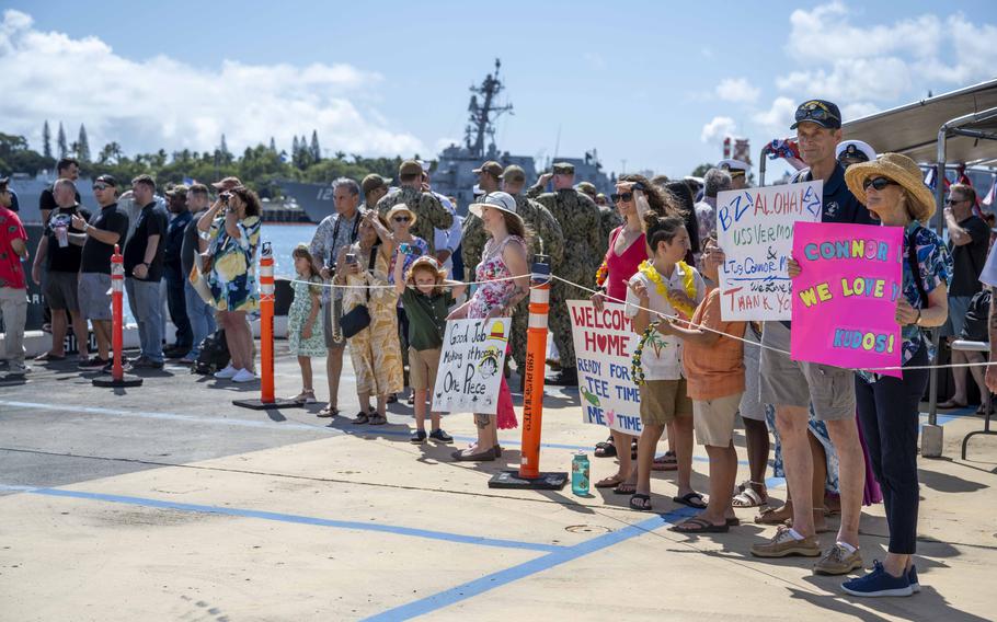 A crowd of people hold up “welcome home” signs 