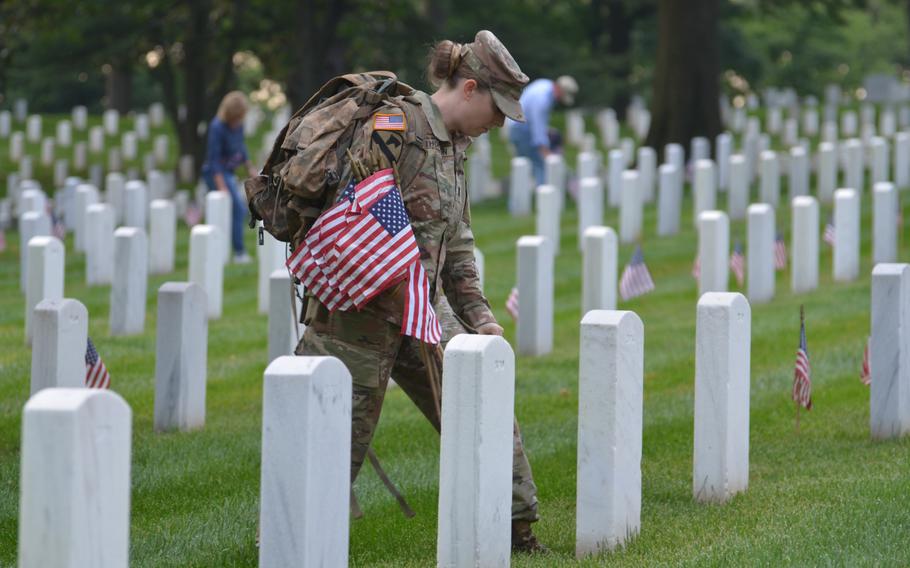 First Lt. Mary Thompson places flags at the graves of those buried at Arlington National Cemetery for “Flags In” on Thursday, May 23, 2024, to honor fallen service members for Memorial Day.  