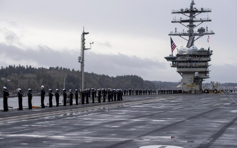 Sailors man the rails on the flight deck of an aircraft carrier