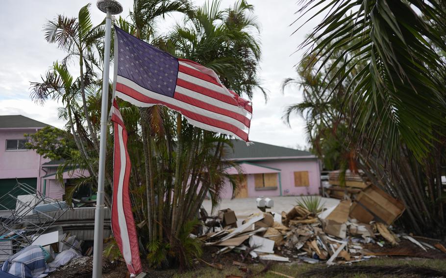 A ripped American flag flies above debris.