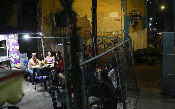 People wait for "arepas" on a street food stand in the Santa Rosalia neighborhood of Caracas, Venezuela, Wednesday, July 24, 2024. The presidential election is set for July 28. (AP Photo/Matias Delacroix)