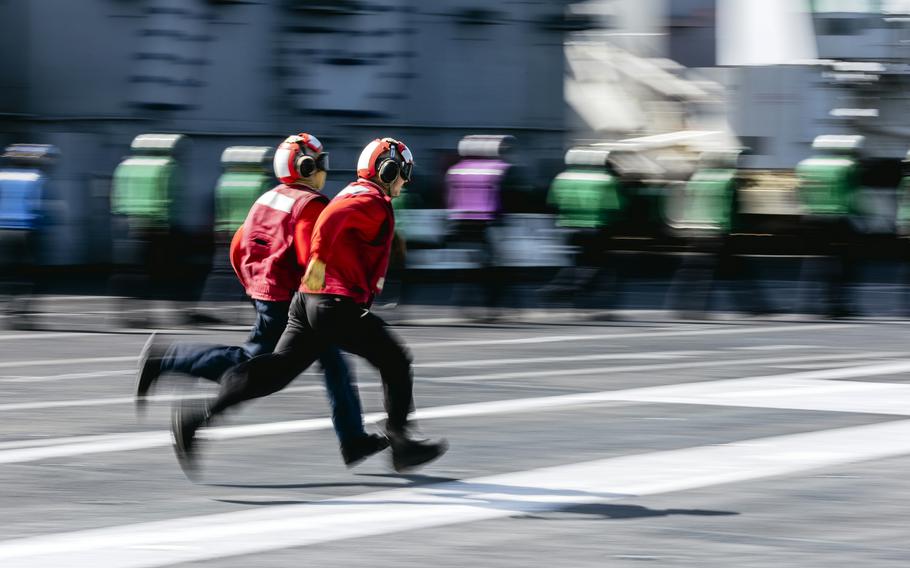 Petty Officer 3rd Class Israel Montano, front, and Airman Erick Telloayaca run on the flight deck of the aircraft carrier USS George Washington while underway in the Pacific Ocean, Aug. 25, 2024. 