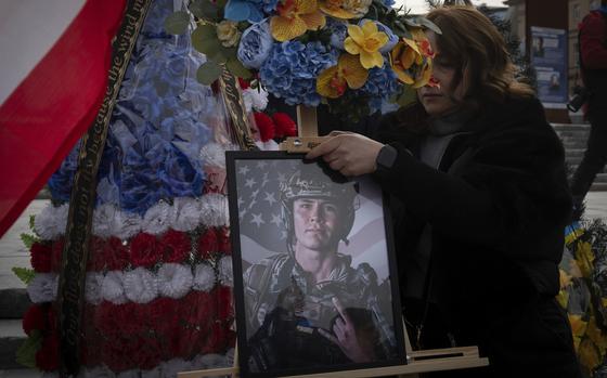 A woman holds a portrait of U.S. Marine Corps veteran Ethan Hertweck, 21, who lost his life in defending Ukraine against the Russian troops.