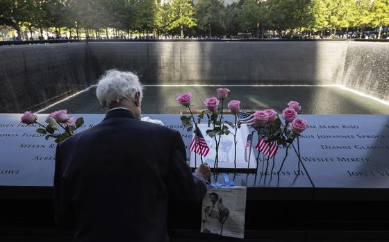 Hagi Abucar places flowers for his former coworker Lindsey Herkness on the south reflecting pool during the 9/11 Memorial ceremony on the 23rd anniversary of the Sept. 11, 2001 attacks, Wednesday, Sept. 11, 2024, in New York. (AP Photo/Yuki Iwamura)