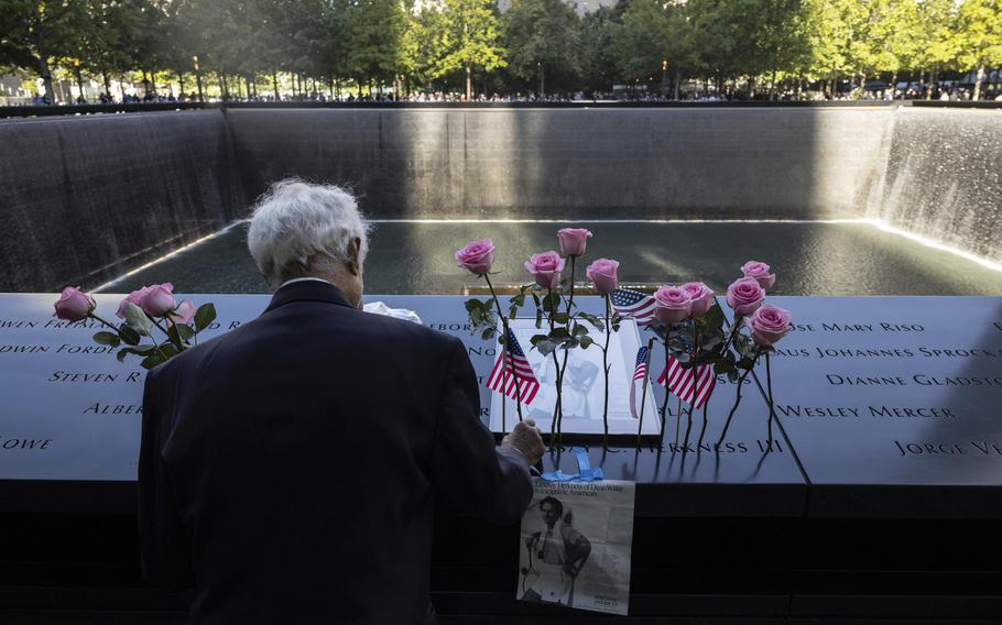 Hagi Abucar places flowers for his former coworker Lindsey Herkness on the south reflecting pool during the 9/11 Memorial ceremony on the 23rd anniversary of the Sept. 11, 2001 attacks.