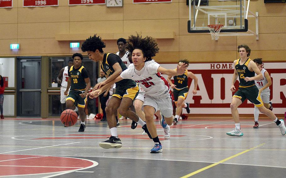 Kaiserslautern's Jordan Balsamo, center, and SHAPE's Yanis Anderson fight for the ball during a Jan. 12, 2024, game at Kaiserslautern High School in Kaiserslautern, Germany.