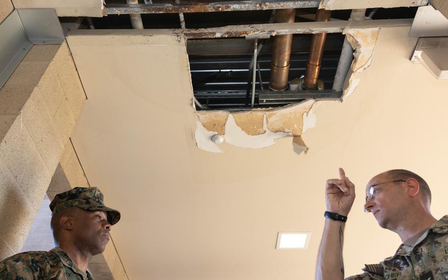 Marines look at a hole in the ceiling of a barracks.