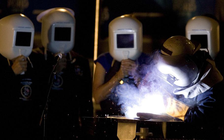 Robert Bowker welds the initials of the ship's sponsor, Susan Ford Bales onto the keel Saturday, Nov. 14, 2009, during the keel laying and authentication ceremony for the Gerald R. Ford carrier (CVN 78) at Northrop Grumman Corp.'s Newport News shipyard.