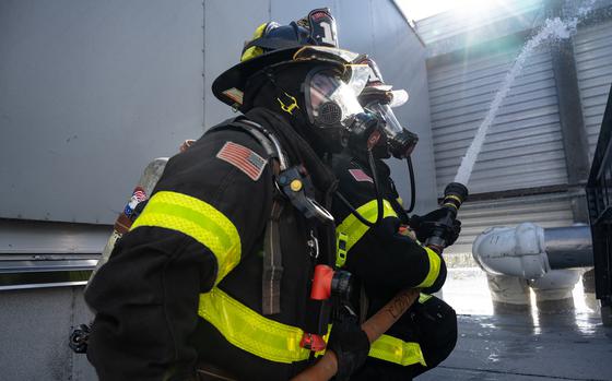 Firefighters aim a water hose at a building.