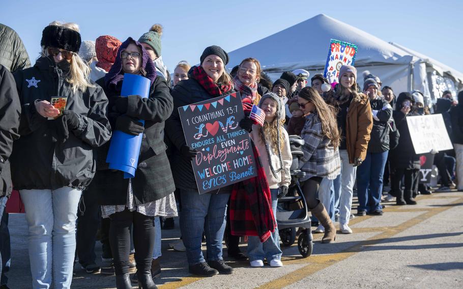 Families of sailors wait pierside for ships to dock.