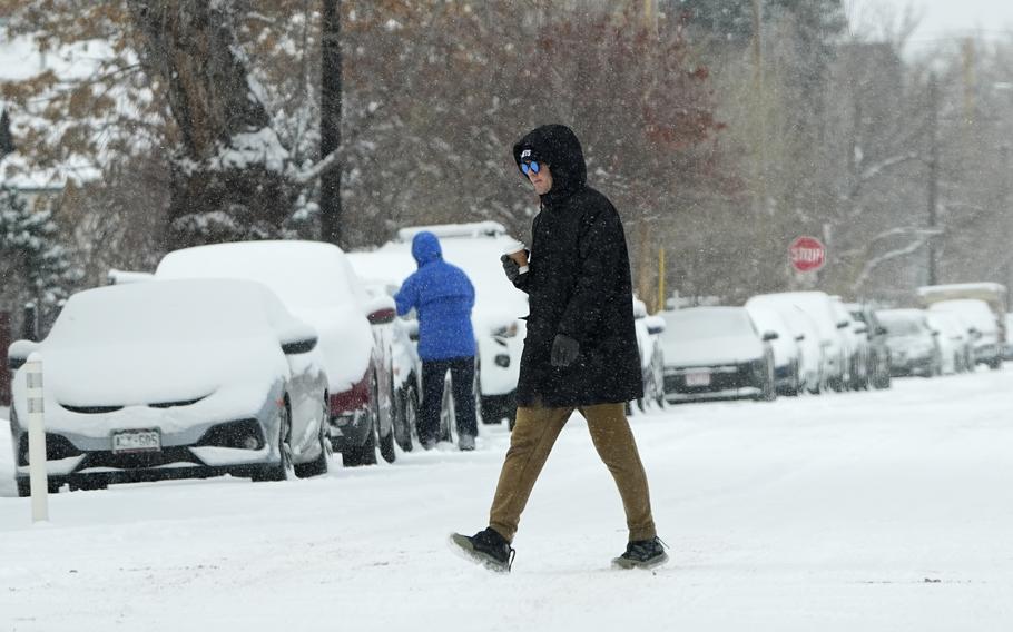 A man crosses a snowy street.