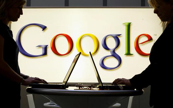 FILE - In this April 17, 2007 file photo, exhibitors work on laptop computers in front of an illuminated sign of the Google logo at the industrial fair Hannover Messe in Hanover, Germany. (AP Photo/Jens Meyer, File)