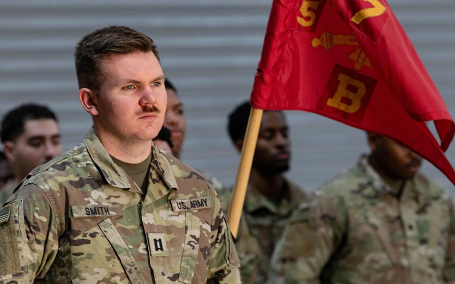 A soldier, with the unit’s flag in the background, looks on during the ceremony.