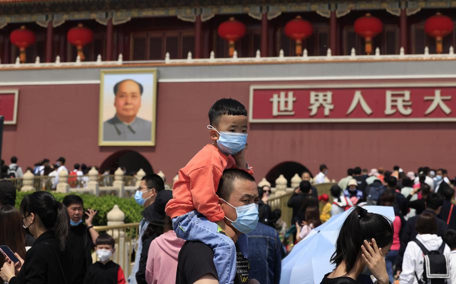 A man and child wearing masks visit Tiananmen Gate near the portrait of Mao Zedong in Beijing on May 3, 2021.