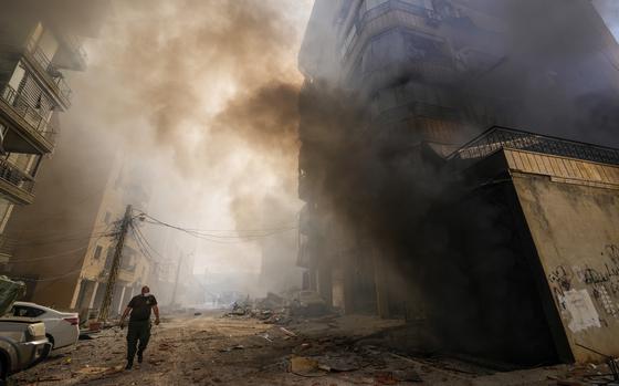 A person walks through smoke next to a building hit by an Israeli airstrike in Lebanon.