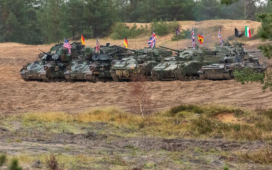 Vehicles with flags representing their countries are lined up in Adazi, Latvia.