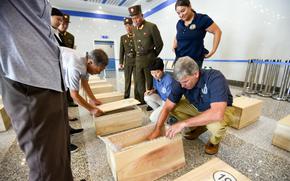 Forensic anthropologists with the Defense POW/MIA Accounting Agency review the contents of cases containing the possible remains of service members lost in the Korean War during a unilateral transfer in Wonsan, North Korea, in July 2018.