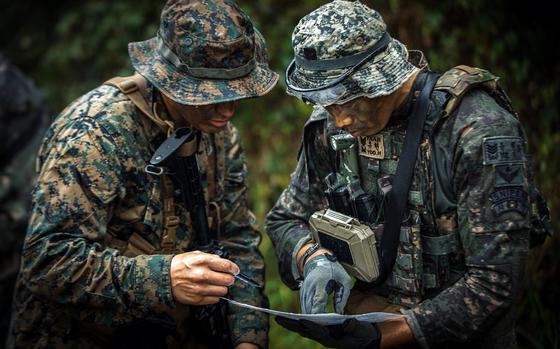 Two service members look over a map. 