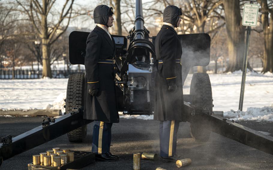 Smoke from a cannon lingers in the air, and shells lie at the feet of two soldiers after they have fired a ceremonial salute.