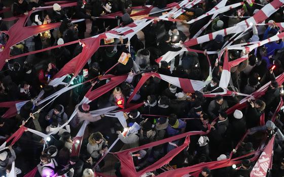 Participants tear a banner representing the flag of the ruling People Power Party during a rally to demand South Korean President Yoon Suk Yeol's impeachment in front of the headquarters of the ruling People Power Party, in Seoul, South Korea, Monday, Dec. 9, 2024. (AP Photo/Ahnn Young-joon)