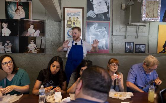 Forrest Beals, center, eats chicken dumplings at Time Out Market in Chicago during a “The Bear” themed food tour on June 21. Chicago Food & City Tours began the themed excursions in November after months of requests from guests. The tour is modeled after Season 2, Episode 3, when sous chef Sydney treks across the city to try different restaurants — not unlike a food tour, said Hannah Gleeson, the company’s director of operations. The three-hour tour remains one of the company’s most popular and is frequently sold out on the Fridays and Saturdays it runs.