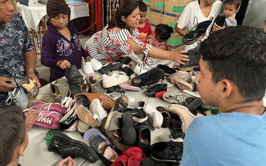 Migrants in a shelter examine donated shoes